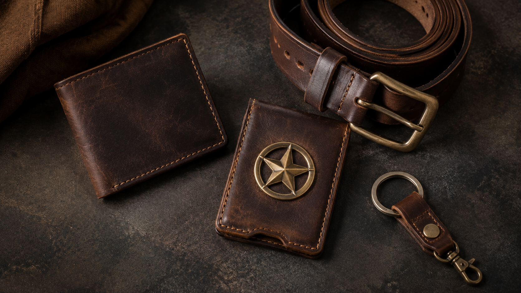 Flat lay of leather goods as gifts including bifold wallet, badge wallet, belt, and key fob on dark surface