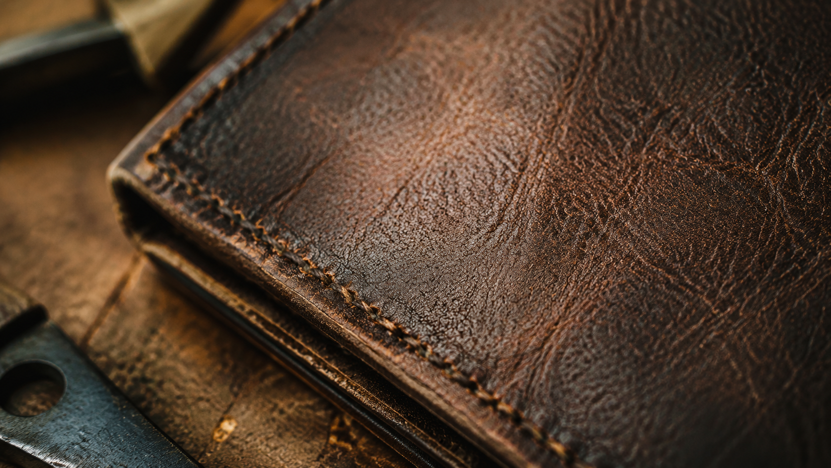 Macro close-up of full-grain leather wallet surface showing natural grain texture and deep warm patina detail